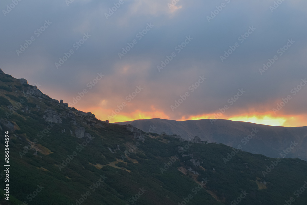 Beautiful sunset view of rock landscape of mountains, forest and meadows in the Carpathians in sunny  cloudy weather