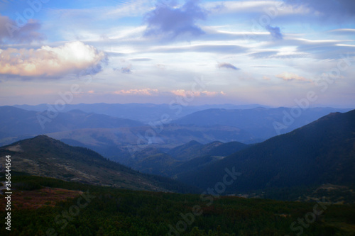 Beautiful sunrise view of landscape of mountains, forest and meadows in the Carpathians in sunny cloudy weather