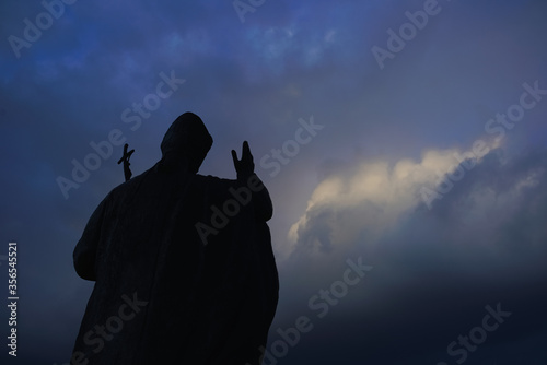 Great big Christian holy statue monument and shrine of Pope John Paul II from Catholic Church Vatican City State against the background of cloudy evening spring winter sky in blue, purple tones