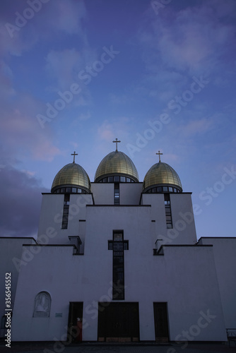 Golden-domed church towers with crosses against dramatic blue and purple twilight skies, highlighting architectural beauty and spiritual symbolism