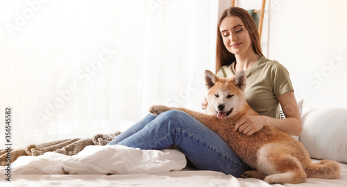 Young woman with her cute Akita Inu dog at home, banner design. Lovely pet