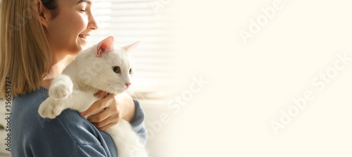 Young woman with her beautiful pet at home, space for text. Banner design
