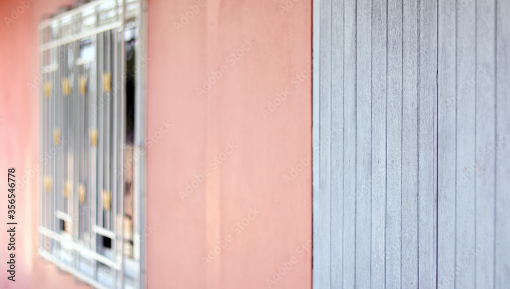 The window home made from white metal with orange concrete cement wall and blue wooden door decoration outside home, vintage style home design concept, selective focus blurred foreground. The window home made from white metal with orange concrete cement wall and blue wooden door decoration outside home, vintage style home design concept, selective focus blurred foreground.