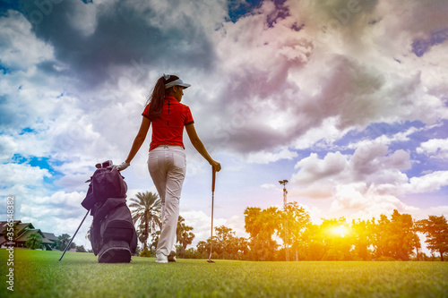 Gorgeous golfer lady with golf equipment in beautiful sunset light