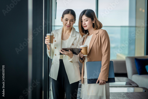 Team work process. Two women with laptop in open space office. Business concept., two women is meeting for business matching. ,Two young beautiful asian business woman in the conversation.