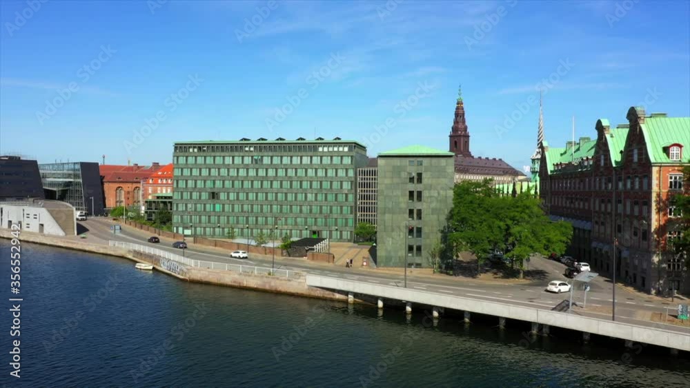 Aerial shot of vehicles on street by buildings and canal, drone ascending forward over cityscape against sky on sunny day - Copenhagen, Denmark Aerial shot of vehicles on street by buildings and canal, drone ascending forward over cityscape against sky on sunny day - Copenhagen, Denmark