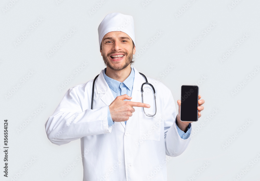 Happy doctor presenting mobile phone with blank screen Happy doctor presenting mobile phone with blank screen