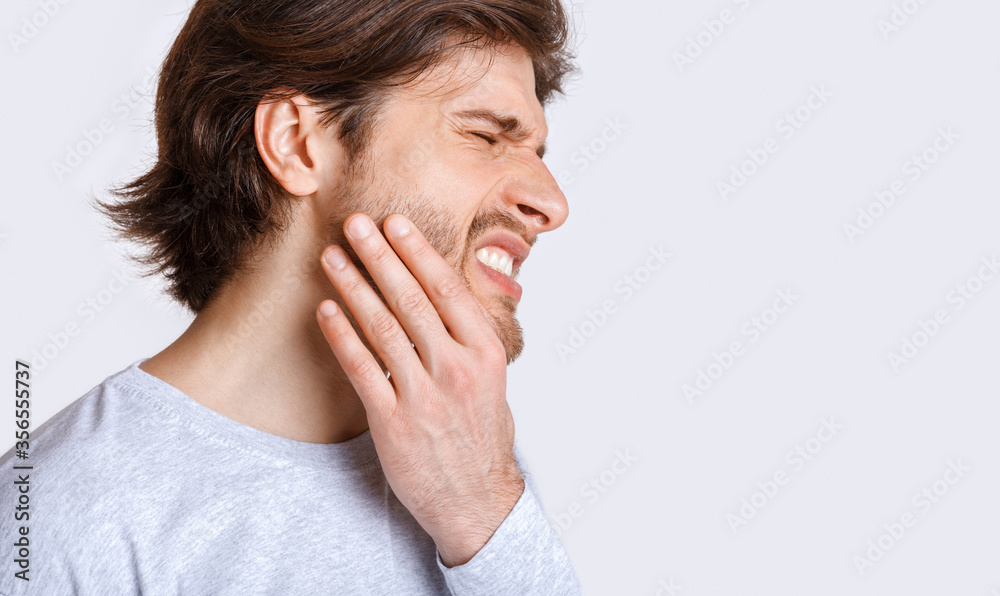 Not tolerate pain in teeth and dentures. Man suffers from pain and presses his hand to cheek Not tolerate pain in teeth and dentures. Man suffers from pain and presses his hand to cheek