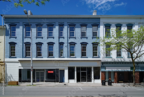 main street facade of old brick buildings with vacant stores at street level and apartments above