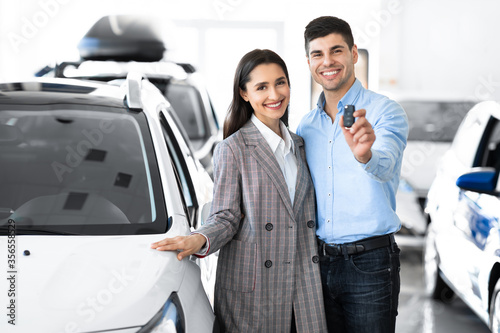 Spouses Showing Car Key Hugging In Dealership Store