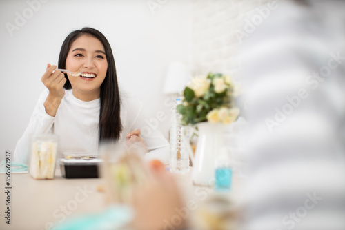 Young Asian  woman sitting separated in restaurant or home  eating food with table protect infection from coronavirus covid-19, new normal restaurant and social distancing concept.