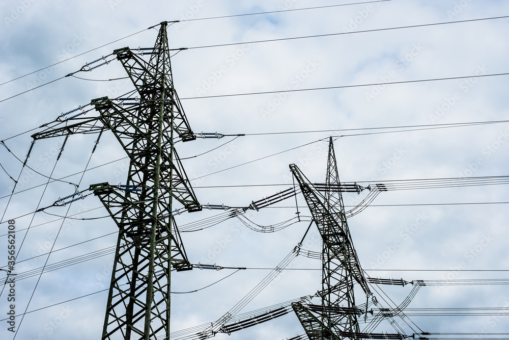 Elektroindustrie: Hochspannungsmast mit Kabeln vor blauem Himmel und weißen Wolken