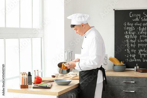 Handsome Asian chef cooking in kitchen