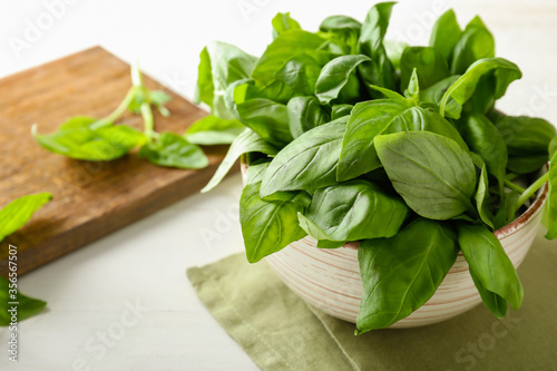 Bowl with fresh green basil on white background