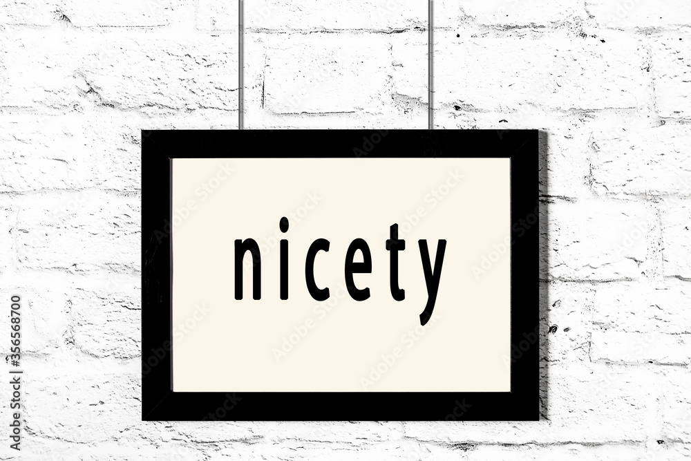 Ταπετσαρία Black frame hanging on white brick wall with inscription nicety