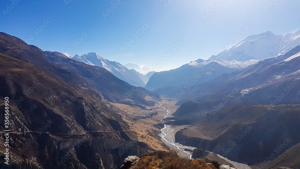 Early morning in Manang Valley, Annapurna Circus Trek, Himalayas, Nepal, with the view on Annapurna Chain and Gangapurna. Dry and desolated landscape. High, snow capped mountain peaks. Small torrent