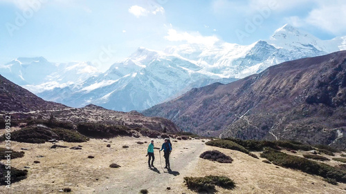 A couple trekking in the Manang Valley, Annapurna Circus Trek, Himalayas, Nepal, with the view on Annapurna Chain and Gangapurna. Dry and desolated landscape. High snow capped mountain peaks. Freedom