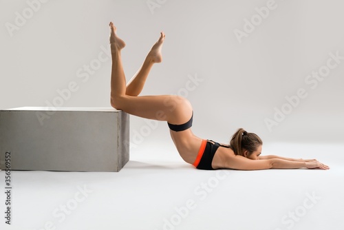 Flexible woman in underwear exercising near block