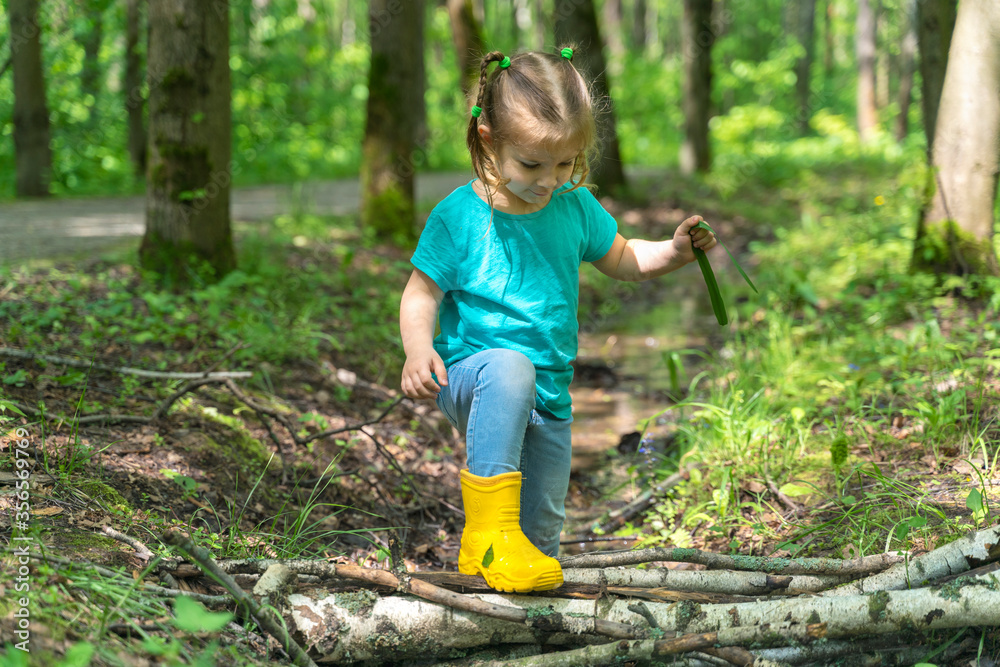little girl walks through puddles in rubber boots in the forest little girl walks through puddles in rubber boots in the forest