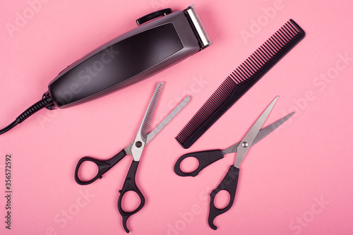 set of tools for haircuts on a pink background, scissors, comb and trimmer