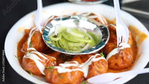 Closeup shot of gravy butter chicken momos topped with mayonnaise dressing and green mint chutney, served on a paper plate. photo