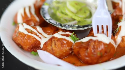 Closeup shot of gravy butter chicken momos topped with mayonnaise dressing and green mint chutney, served on a paper plate. photo