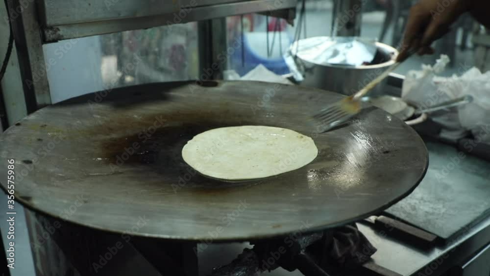 Cooking Indian bread parantha on a huge Indian pan at a street food restaurant. Cooking Indian bread parantha on a huge Indian pan at a street food restaurant.