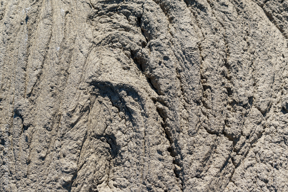 Wall of solid concrete. Wrinkled surface, cracks. Grey colour.