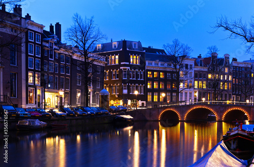 The Netherlands. A beautiful view of Amsterdam at night with a reflection in the canal of the bridge and traditional Dutch houses on the waterfront