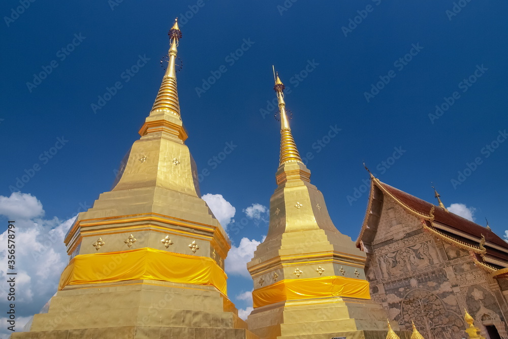 Fototapeta premium view of ancient golden pagoda (Phra Phutthabat Huai Tom) with blue sky background, Wat Phra Phutthabat Huai Tom, Li District, Lamphun, northern of Thailand.