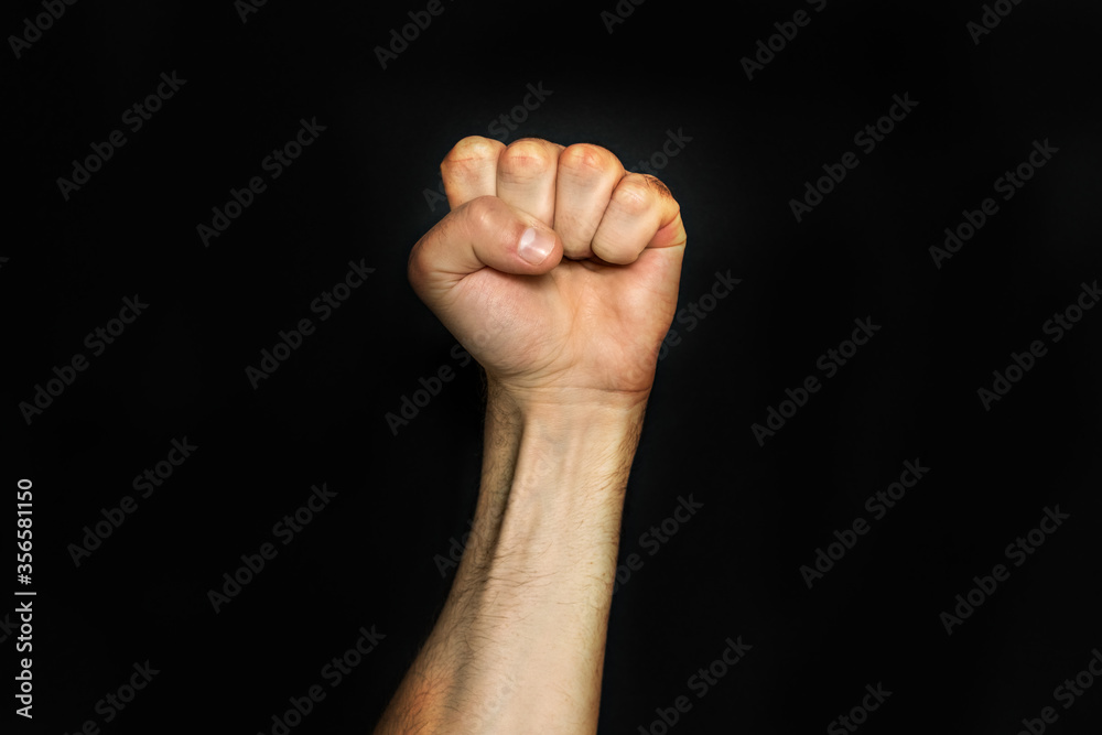 Male fist on a black background. Aggressiveness, masculinity, the concept of challenge