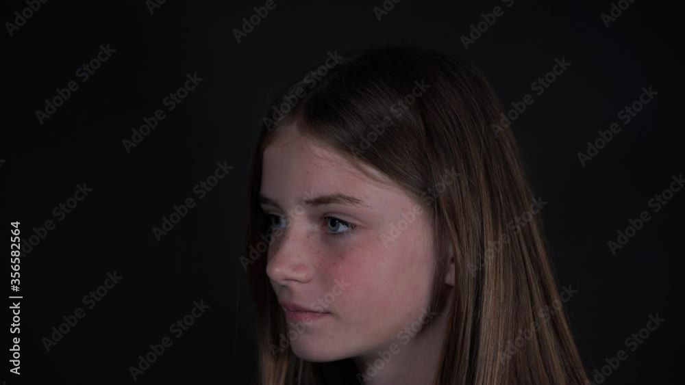 Beautiful blond young girl with freckles indoors on a black background, close up portrait Beautiful blond young girl with freckles indoors on a black background, close up portrait