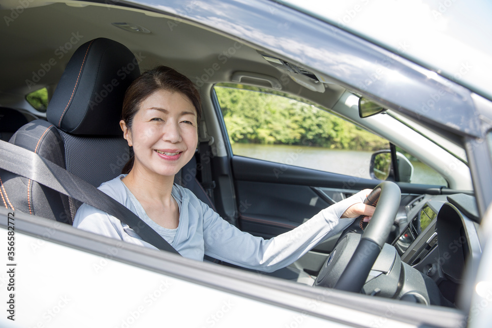 運転をするミドルの女性、新緑のドライブ