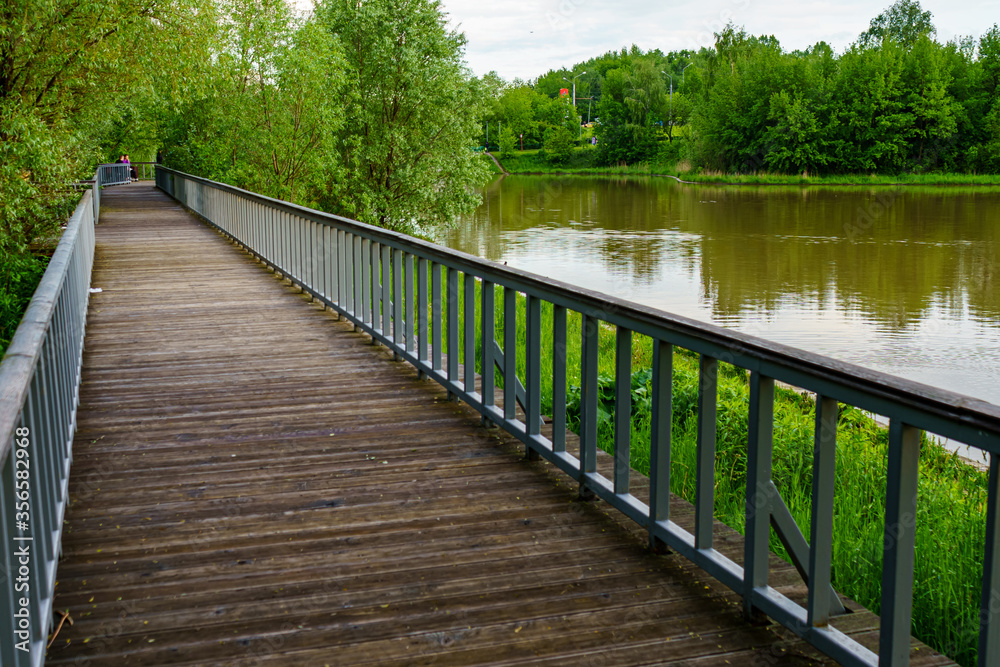 Wooden boardwalk in a Moscow park by the pond