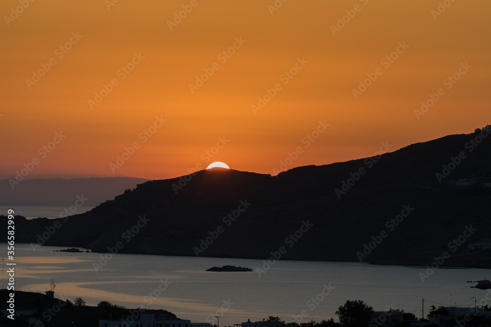 Orange Sunset. Isolated. Sun behind silhouetted mountain. Stock Image.