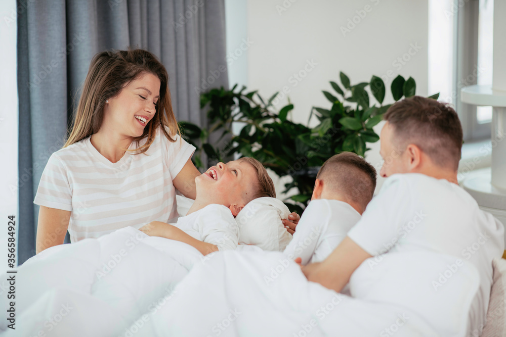 Young family enjoying at home. Happy parents with sons relaxing on sofa.	