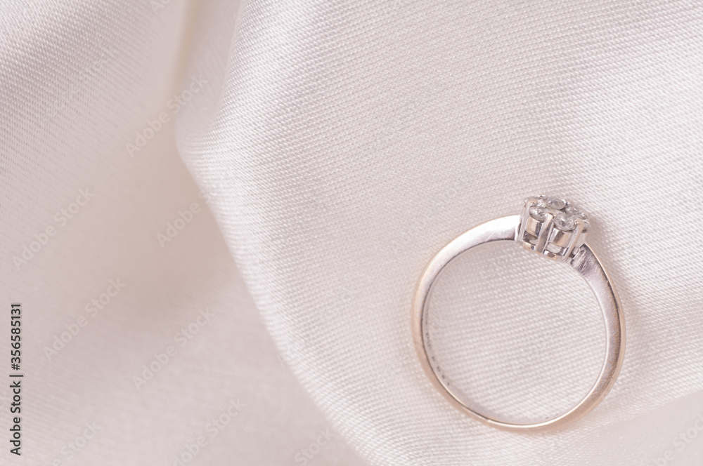 Wedding rings/ Engagement ring with diamonds isolated over white satin cloth Wedding rings/ Engagement ring with diamonds isolated over white satin cloth