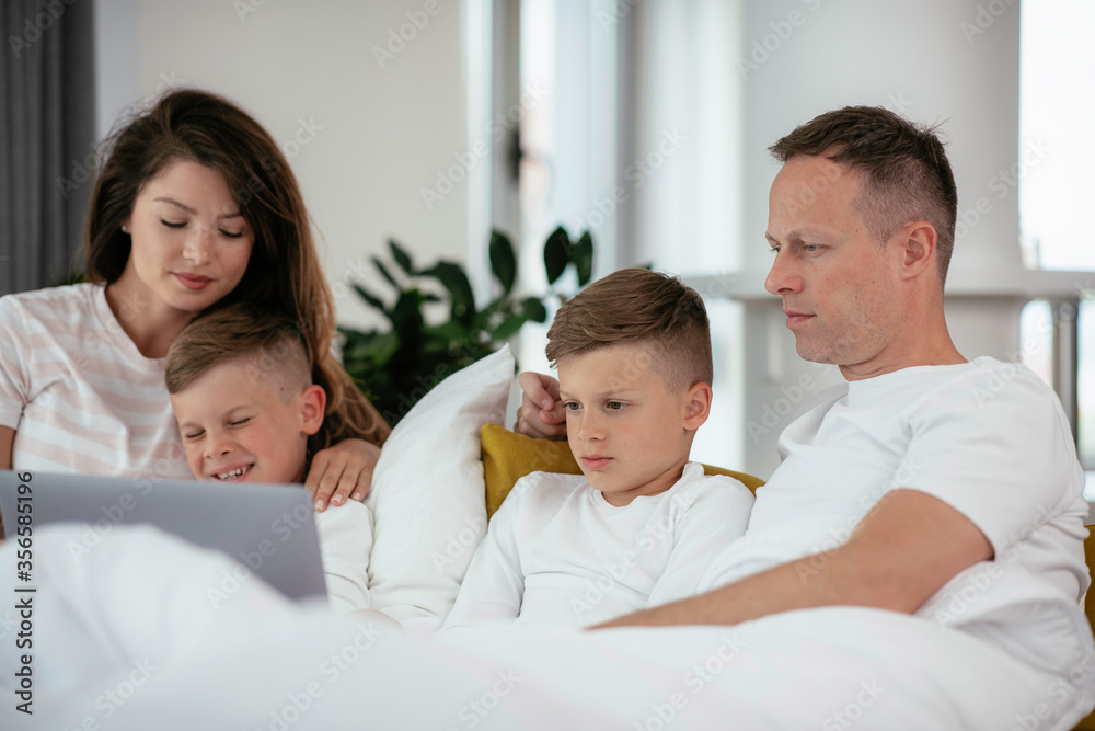 Young family watching movie on lap top. Beautiful parents with kids enjoying at home. Young family watching movie on lap top. Beautiful parents with kids enjoying at home.