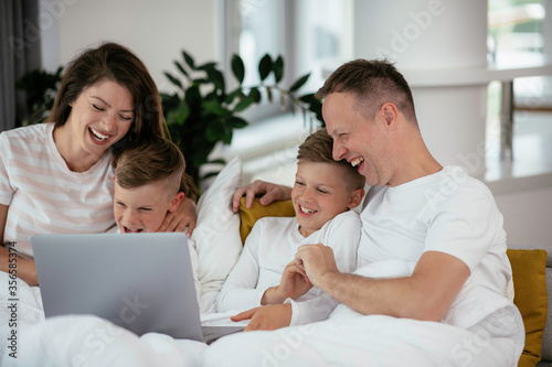 Young family watching movie on lap top. Beautiful parents with kids enjoying at home. 