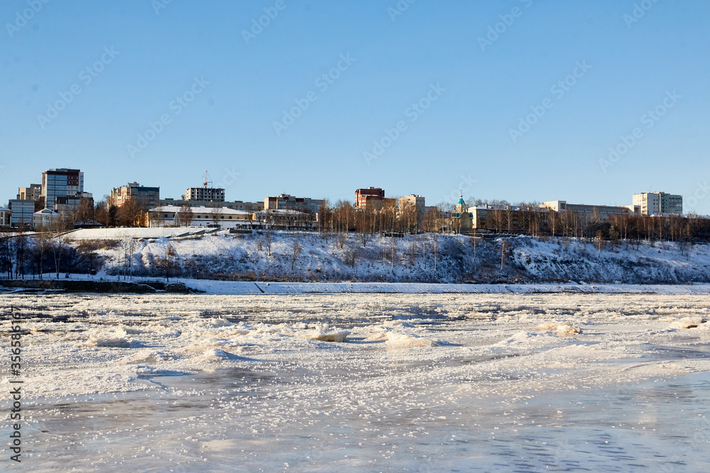 Ice on the river on a Sunny winter day and city on background. Ice texture and background.