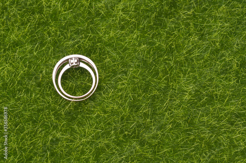 A pair of wedding/engagement ring isolated over green grass