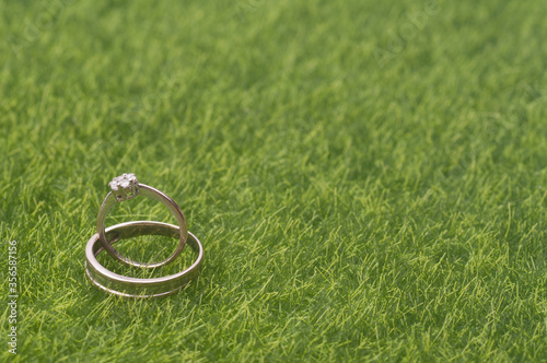 A pair of wedding/engagement ring isolated over green grass