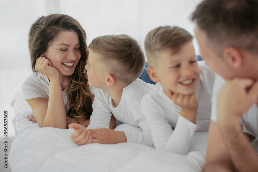 Young family enjoying in bed. Happy parents with sons relaxing in bed. Young family enjoying in bed. Happy parents with sons relaxing in bed.