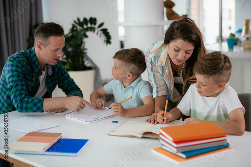 Parents helping the kids with their homework. Litlle boys learning at home.