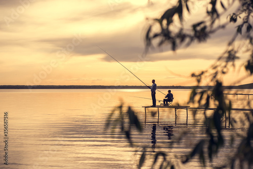 fishermen are on the lake during sunset