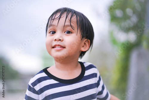 portrait of cute little happy asian boy smiling in a park