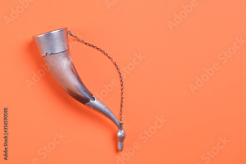 Georgian traditional horn for wine drinking. Curved horn isolated on bright orange background. Copy space.
