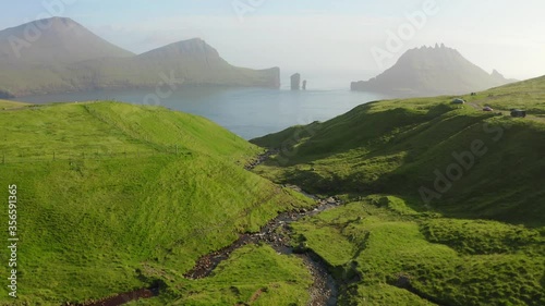 4k drone footage (Ultra High Definition). Colorful summer scene of Faroe Islands and Tindholmur cliffs on background. Misty morning view of Vagar island, Denmark, Europe. Traveling concept background photo