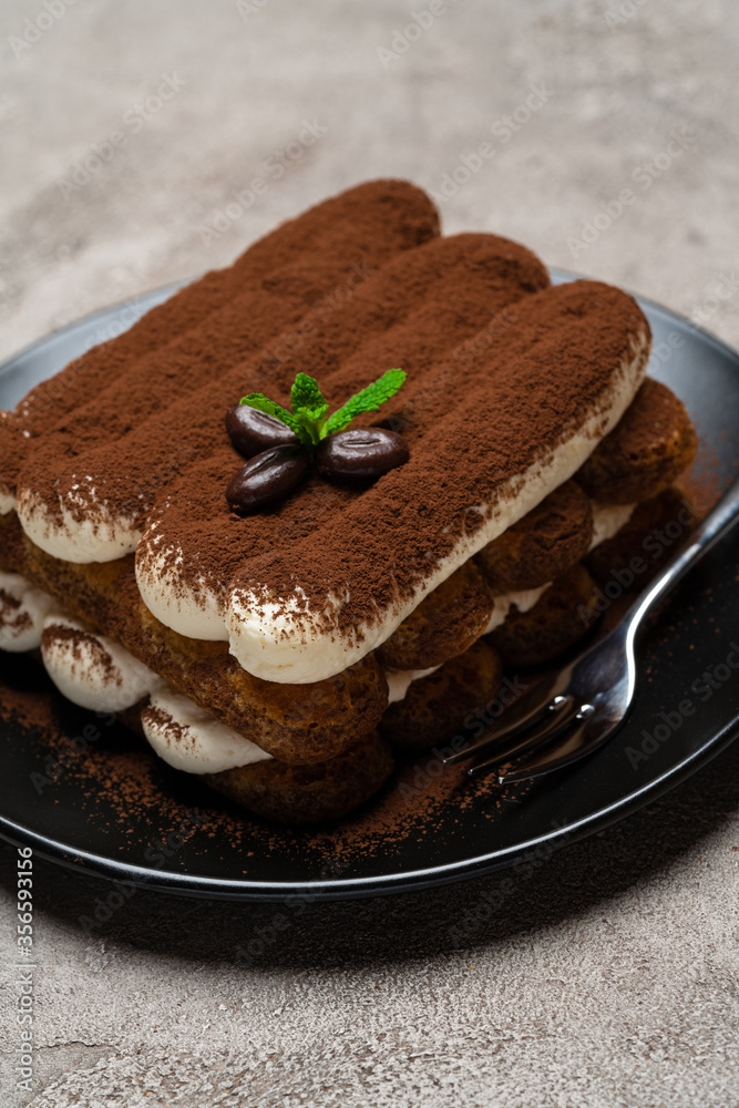 Classic tiramisu dessert on ceramic plate on light grey concrete background Classic tiramisu dessert on ceramic plate on light grey concrete background