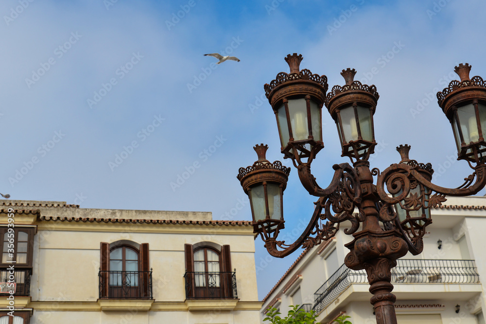 Antique bronze lantern on the background of typical Spanish buildings.